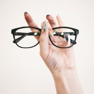 Hand holding a pair of black eyeglasses frames