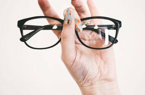 Hand holding a pair of black eyeglasses frames